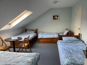 丁格尔Coastguard Lodge Hostel at Tigh TP的一间设有两张床和一张桌子及椅子的房间