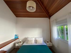 圣塞巴斯蒂安Ao Mar - Hospedagem的一间卧室配有一张蓝色的床和木制天花板