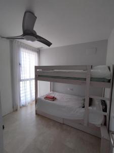 埃尔韦尔赫尔Apartamento bonito - playas las Deveses的一间卧室设有两张双层床和吊扇