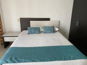 博卡德尔里奥Apartamentos Frente a La Playa Boca del Rio的一张带两个蓝色枕头的床和一张书桌