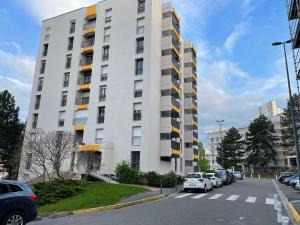 Saint EtienneBel appartement composé de deux chambres的一座高大的白色建筑,汽车停在停车场