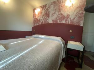 莱万托玛格丽塔别墅酒店的一间卧室配有一张大床和红色床头板