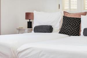 克拉伦代克Villa Aventura的一张带枕头的白色床和一张桌子上的台灯