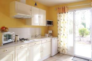 Massillargues-AttuechAnduze Gîte Les Pins au "Petit Clos des Cigales"的厨房配有白色橱柜、水槽和窗户。
