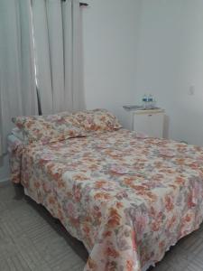 阿拉鲁阿马Recanto Suítes的一间卧室配有一张带鲜花毯子的床