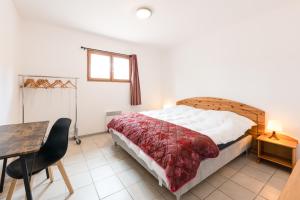 蒙布兰莱班La Tour de Guet的一间卧室配有一张床、一张桌子和一张桌子。