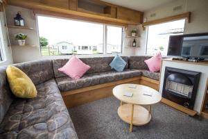 Great 4 Berth Caravan At Withernsea Sands Ref 79003hg的带沙发、电视和桌子的客厅