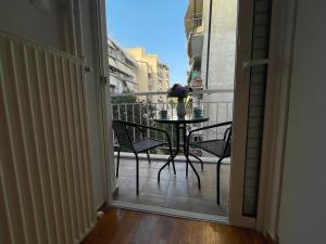 雅典Traveller's Choice Attiki的通往带桌椅的阳台的开放式门