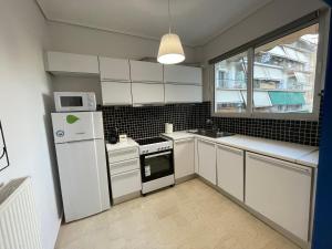 雅典Traveller's Choice Attiki的厨房配有白色橱柜和白色冰箱。