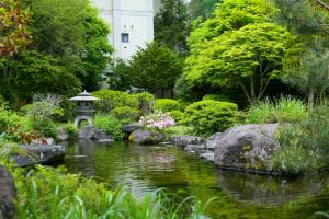 上田市Ooedo Onsen Monogatari Kakeyu的一个带池塘、岩石和树木的花园