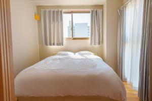 大阪DC桜の苑401洋式双人床的卧室内的一张白色床,设有窗户