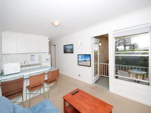尼尔森湾Beachside Shoal Bay Unit 2的厨房以及带桌椅的起居室。