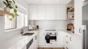 浅滩湾Luxury Escape Sundeck Shoal Bay的白色的厨房配有白色橱柜和水槽