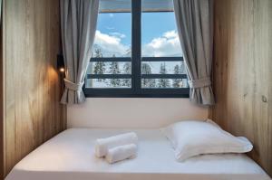 La Plagne TarentaiseChalet Hôtel Turquoise的窗户客房内的一张床位