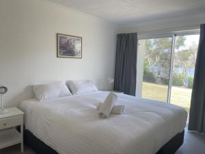金德拜恩Banksia 1的卧室配有一张白色的床,上面有一只动物填充物