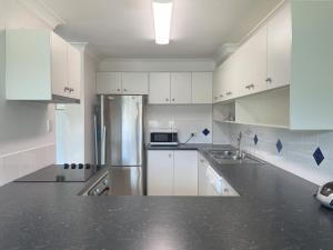 金德拜恩Banksia 1的厨房配有白色橱柜和不锈钢冰箱