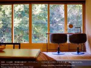 伊豆龙田日式旅馆的窗户前配有一张桌子和两把椅子的房间