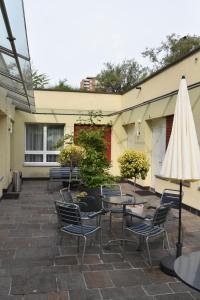 巴塞尔商业酒店的庭院配有桌椅和白色遮阳伞