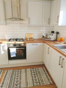 诺丁汉Cosy Family Home in Long Eaton, Nottingham的厨房配有白色橱柜和炉灶烤箱。