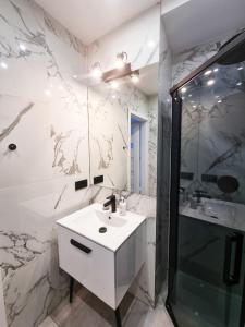 罗兹Kamienica Łódzka的白色的浴室设有水槽和淋浴。