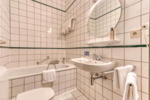 圣胡伯特Hôtel Le Cor de Chasse的白色瓷砖浴室设有水槽和卫生间