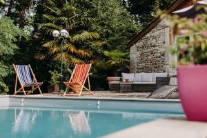 奥尔泰兹Le moulin des Sens - SPA-SAUNA的游泳池畔的两把椅子和一张沙发