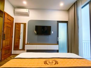 潘郎Khách sạn Miami Ninh Thuận的卧室配有一张床,墙上配有电视。