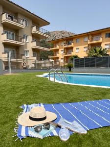 埃斯塔蒂特热带公寓RV酒店的游泳池旁的毯子上戴着帽子和太阳镜