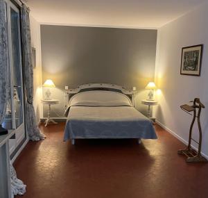 格里莫LA MAISON DE JUSTINE的一间卧室配有一张床,两盏台灯放在两张桌子上