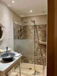 格里莫LA MAISON DE JUSTINE的一间带玻璃淋浴和水槽的浴室