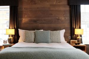 OdihamThe Red Lion的一间卧室配有一张带木制床头板的床和两盏灯。