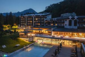 科马诺泰梅Grand Hotel Terme Di Comano的一座大型建筑,在晚上前设有一个游泳池