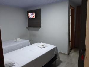 Telêmaco BorbaHotel ROF的配有两张床铺的客房,墙上配有电视