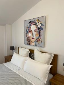 波伊奥卡萨奥姆诺旅馆的一张带白色枕头的床和墙上的绘画