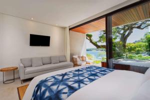伊利亚贝拉Wyndham Ilhabela Casa Di Sirena的一间卧室配有一张床、一张沙发和一个窗口