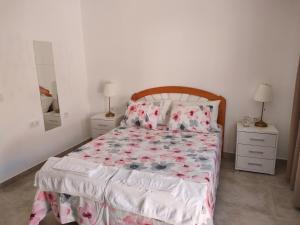 罗萨里奥港Casa Alba 2的一间卧室配有一张带花卉床罩和2个床头柜的床。