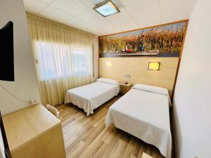 托尔托萨托尔托萨公园酒店的一间医院房间,配有两张床和墙上的绘画