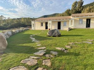 特乌拉达Is Arenas Biancas Agriturismo的一座带石头路的草场的房子