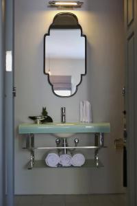 罗威那Lovinalife Room & Cafe的浴室配有带镜子的盥洗盆和毛巾