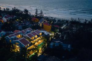 会安CHiEM HoiAn - The Beachside Boutique Hotel & Villa的海滩上灯火通明的房子的空中景色