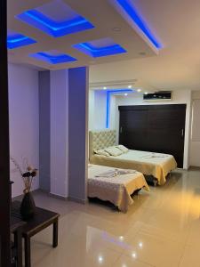 巴耶杜帕尔Aparta Hotel El Cacique Upar的天花板上设有蓝色灯光的客房内的两张床