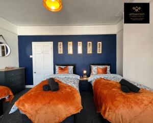 滨海绍森德Vintage Vibes By Artisan Stays in Southend-On-Sea I PVT Parking I Weekend offer的卧室设有两张床,配有蓝色的墙壁和橙色床单