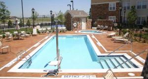威奇托Residence Inn by Marriott Wichita East At Plazzio的一座带椅子的大型游泳池和一座建筑