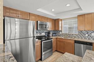 Point O'RocksIsland House Beach Resort 25的厨房配有木制橱柜和不锈钢冰箱。