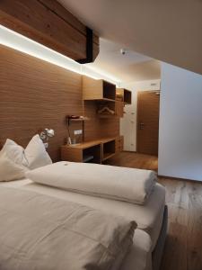 多比亚科Hotel Dolomiten的卧室配有一张白色大床和一张书桌