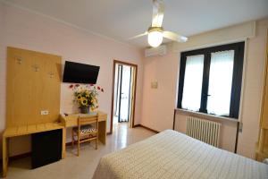 西尔米奥奈费奥达里索酒店的一间卧室配有一张床、一张书桌和一台电视。