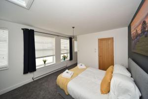 麦克尔斯菲尔德Pinfold Suite - Chester Road Apartments By的一间卧室设有一张大床和两个窗户。
