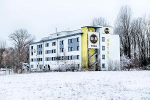 哈尔伯格摩斯B&B HOTEL München-Airport的雪地中的一座建筑,前面有一片田野