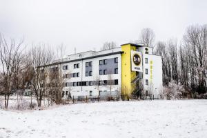 哈尔伯格摩斯B&B HOTEL München-Airport的雪中的一个黄色和白色的建筑