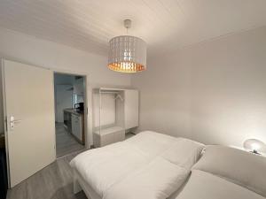 赫恩Möblierte EG- Wohnung zentral in Herne mit Parkplatz,WLAN und Netflix的卧室配有白色的床和吊灯。